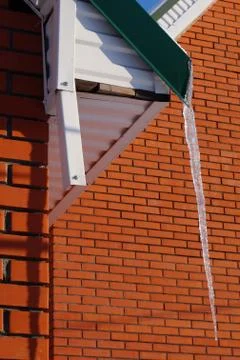 Many large and sharp icicles hang on the roof of the house. Stock-Fotos