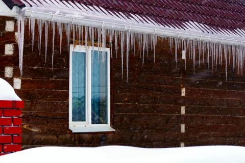 Many large and sharp icicles hang on the roof of the house. Foto stock