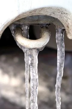 Many large and sharp icicles hang on the car. Stock Photos