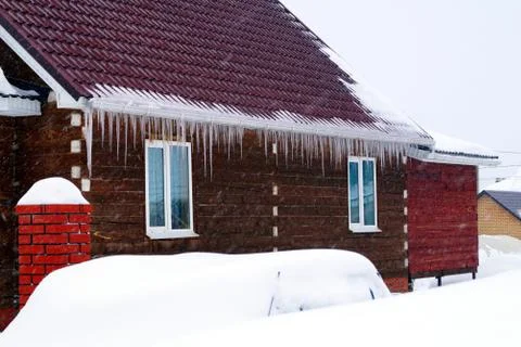 Many large and sharp icicles hang on the roof of the house. Foto stock
