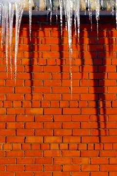 Many large and sharp icicles hang on the roof of the house. Stock Photos