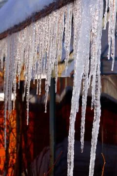 Many large and sharp icicles hang on the roof of the house. Stock Photos