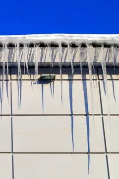 Many large and sharp icicles hang on the roof of the house. Foto stock