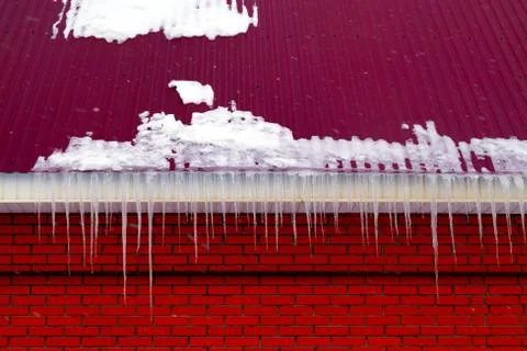 Many large and sharp icicles hang on the roof of the house. Foto stock