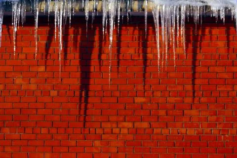 Many large and sharp icicles hang on the roof of the house. Stock-Fotos