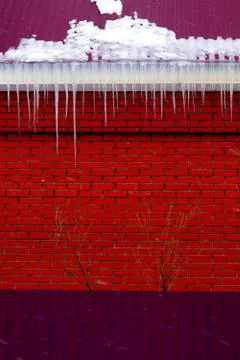 Many large and sharp icicles hang on the roof of the house. Stock Photos