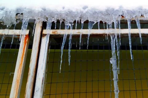 Many large and sharp icicles hang on the roof of the house. Stock Photos