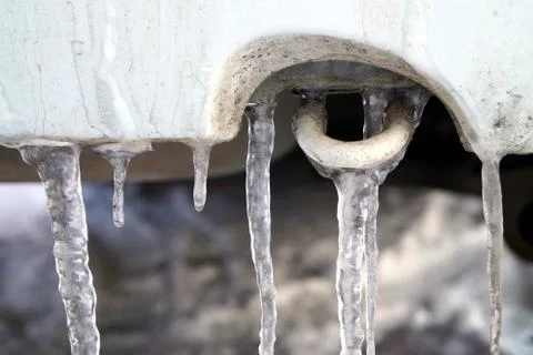 Many large and sharp icicles hang on the car. Stock Photos