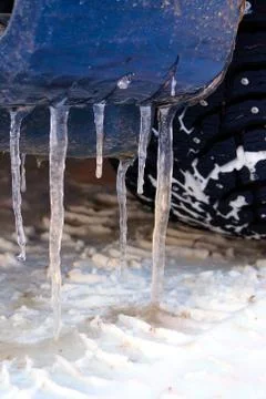 Many large and sharp icicles hang on the car. Stock Photos