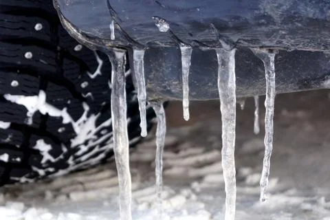 Many large and sharp icicles hang on the car. Stock Photos