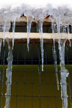 Many large and sharp icicles hang on the roof of the house. Stock Photos