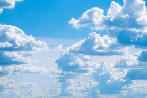 Many large fluffy clouds with a flat bottom against a large bright blue sky with Stock Photos