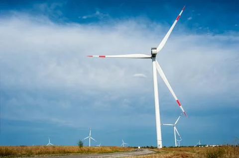 Many large wind generators in a field against the background of the sky and c Stock Photos