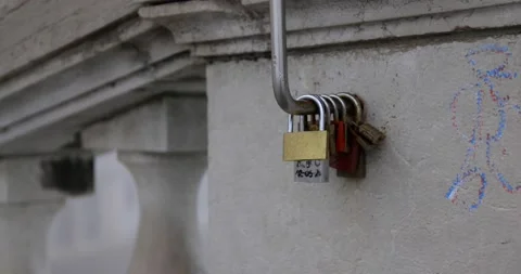 Many locked padlocks hanging on a metallic tube attacked to a wall with columns Stock Footage 150198048