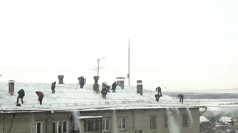 Many men throw white snow from the roof of a multi-storey building. Stock Footage 105667157