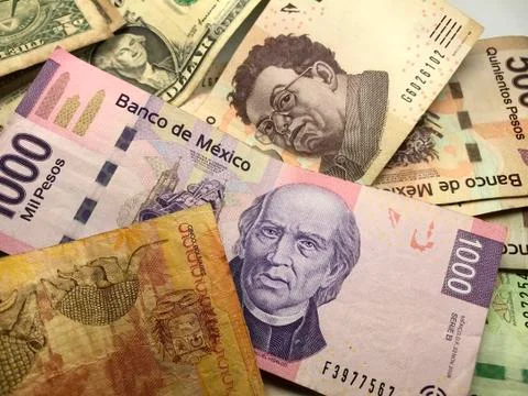 Many mixed Mexican peso bills spread over a wooden desk Stock Photos
