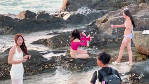 Many models and photographers working simultaneously on the rocky shore Stock Footage 327913394