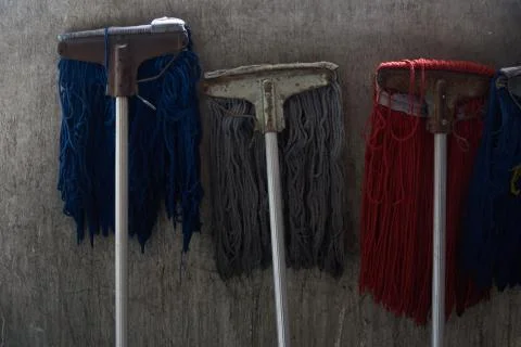 Many mops in different colours leaning against the wall Stock Photos