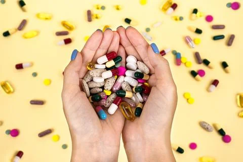 Many multi-colore pills in the hands of a woman against the background. Stock Photos