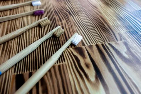 Many multi-colored bamboo toothbrushes lie on a wooden background. eco friendly. Stock Photos