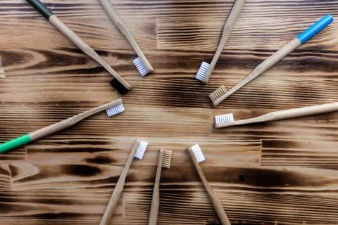 Many multi-colored bamboo toothbrushes lie on a wooden background. eco friendly. Stock Photos