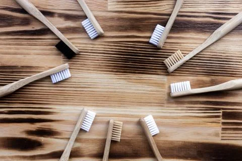 Many multi-colored bamboo toothbrushes lie on a wooden background. Foto stock