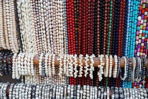 Many multi-colored beads and bracelets hang on the counter Stock Photos