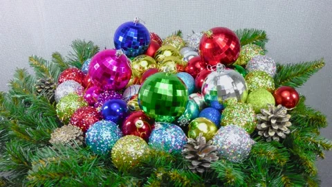 Many multi-colored Christmas balls among the Christmas tree branches and cones Stock Footage 159738601