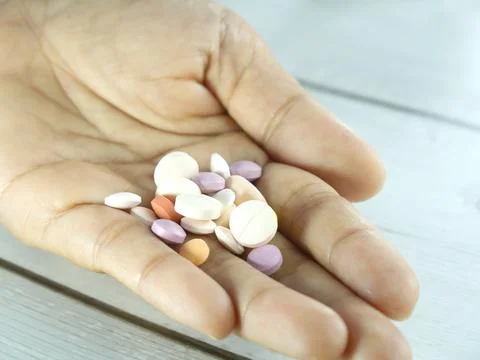 Many multi-colored pills in hand. Stock Photos