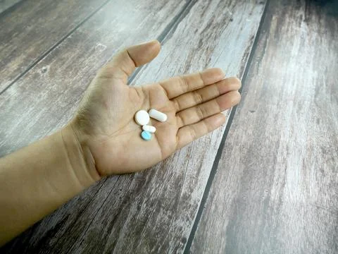 Many multi-colored pills in hand. Stock Photos