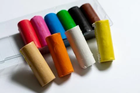 Many multi-colored plasticine sticks lie on a white background. Stock Photos