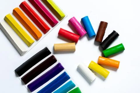 Many multi-colored plasticine sticks lie on a white background. Stock Photos