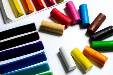 Many multi-colored plasticine sticks lie on a white background. Stock Photos