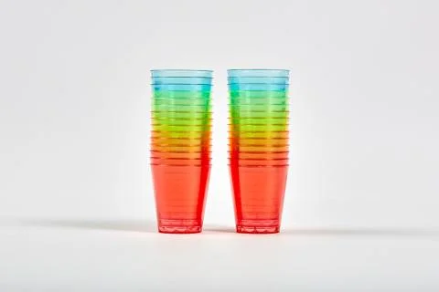 Many multi-colored rainbow colored plastic glasses are stacked together. Stock Photos