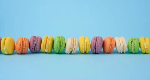 Many multi-colored round baked macarons cakes on a light blue background Stock Photos