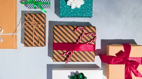 Many multicolored Christmas gift boxes with red ribbon on grey background. Stock Footage 221790340