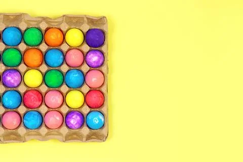 Many multicolored easter eggs in egg box on yellow background Stock Photos
