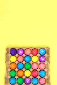 Many multicolored easter eggs in egg box on yellow background Stock Photos