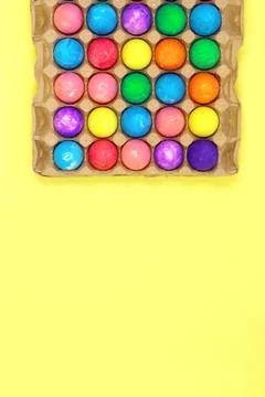 Many multicolored easter eggs in egg box on yellow background Stock Photos