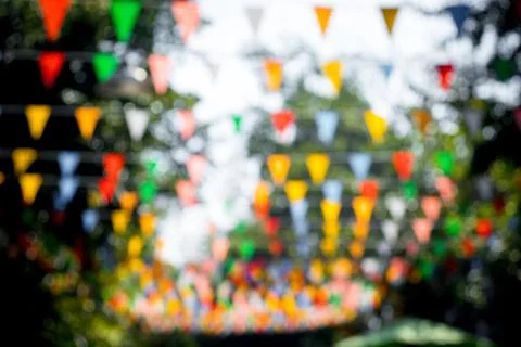 Many multicolored triangular flags adorn the blurred garden. Stock Photos