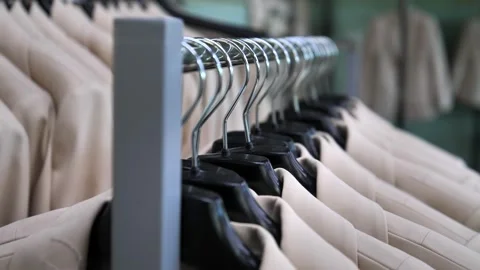 Many new beige jackets hang on a hanger in the store. Stock Footage 247828152