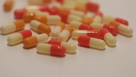 Many nice orange capsules are falling on a white background. Stock Footage 250488782