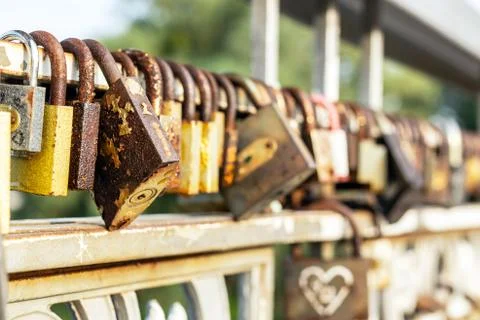 Many old rusty metal locks closed on fence of bridge over river. Love forever Stock-Fotos