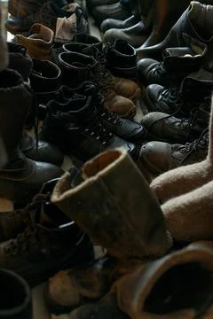 Many old work boots stand together. Old worn construction boots of workers. Real Stock Photos