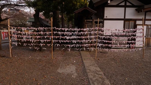 Many Omikuji papers hang on strings between poles, inner yard of Yasukuni Shrine Stock Footage 127934638