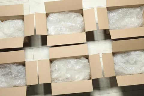 Many open cardboard boxes with bubble wrap on white wooden floor, flat lay Stock Photos