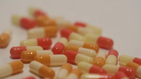 Many orange capsules are falling on a white background. Stock Footage 250488756