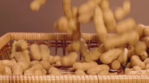 Many peanuts fall into the woven basket in slow motion Stock Footage 76887801
