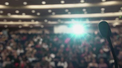 Many people sit in large hall at conference. Projector light via the microphone Stock Footage