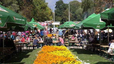 Many people walk or sit at tables eating balkan dishes at street food festival Stock Footage